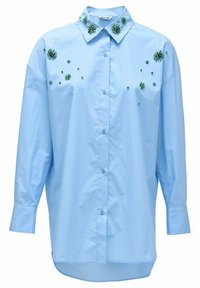 Camisa abotonada de color azul claro con adornos florales en verde esmeralda y pequeños remaches. Presenta un collar clásico y mangas largas.