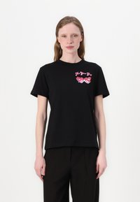 Musta puuvillainen t-paita, jossa on pyöreä kaula-aukko ja lyhyet hihat. Etupuolella on pinkit aurinkolasit ja teksti "Not Your Girl."