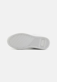 Hvit sneakersåle med en teksturert overflate med diamantmønster og rygger for grep. Logo preget nær hælen.