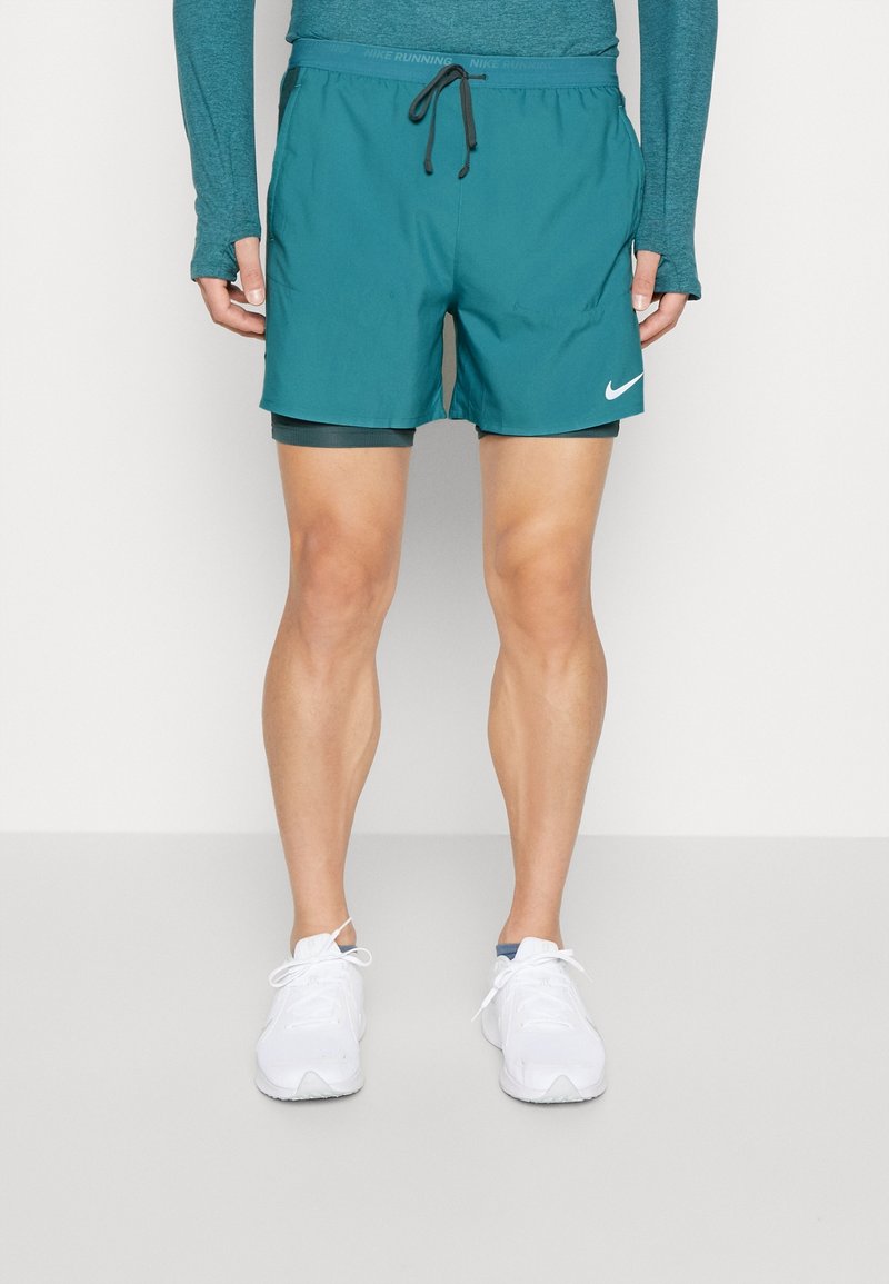 Teal löpshorts med svart dragsko, snabbtorkande material, innertyg och sidofickor. Har en vit Nike-logga på framsidan.