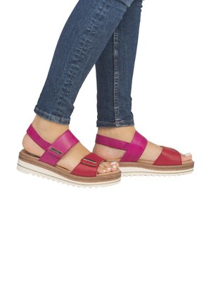 Pink and red women's sandals with wide straps, textured sole, and decorative metallic accents. Wedge design provides lift and comfort.