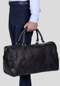 Musta punottu nahkainen viikonloppulaukku, jossa on sileät nahkaosat ja tukevat kahvat, soikea muoto ja sivutasku lisävarastointia varten.