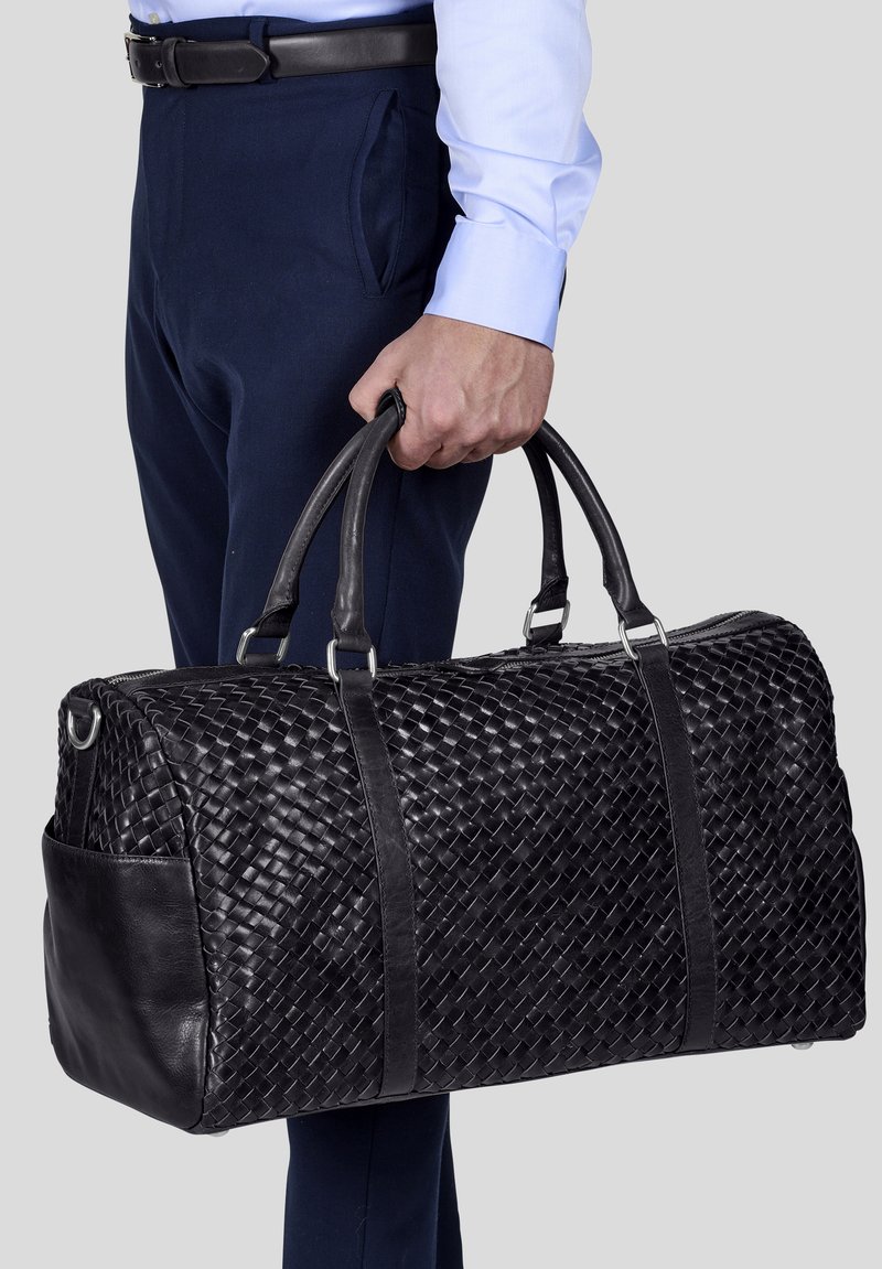 Musta punottu nahkainen viikonloppulaukku, jossa on sileät nahkaosat ja tukevat kahvat, soikea muoto ja sivutasku lisävarastointia varten.