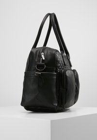 Black leather handbag with a quilted texture, dual handles, multiple zipper pockets, and a spacious design. Features polished hardware accents.