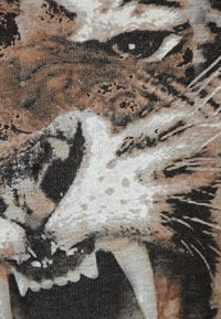 Camiseta gráfica que presenta un primer plano de un tigre rugiente, con un detalle en el patrón de pelaje marrón y gris, resaltando los dientes afilados y los ojos intensos.