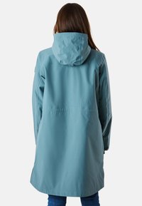 Cappotto impermeabile azzurro chiaro con cappuccio, caratterizzato da una texture liscia, lunghezza a metà coscia e spacchi laterali per facilitare i movimenti.