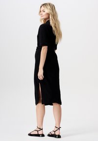 Czarna midi sukienka z krótkimi rękawami, bocznym rozcięciem, prążkowaną fakturą i wiązaniem w talii. W zestawie z płaskimi czarnymi sandałami na paski.