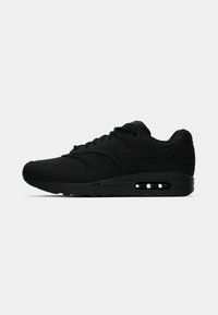 Sorte Nike Air Max sneakers med en glat overdel, rund tå, tyk sål, snørebånd foran og synlig luftdæmpning i hælen.