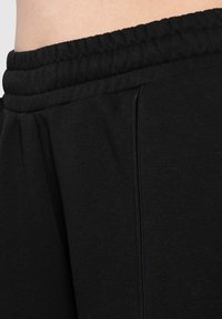 Sorte sweatpants med elastisk talje, blød tekstur og diskrete sidesøm detaljer. Designet til komfort og bevægelsesfrihed.
