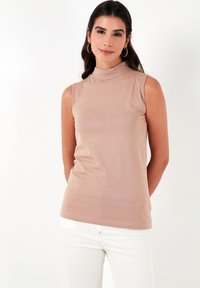 Svijetlosmeđa bezrukavna majica s lažnim ovratnikom napravljena od mekog materijala, s elegantnim dizajnom i suptilnom teksturom. Nema uzoraka ni dodataka.