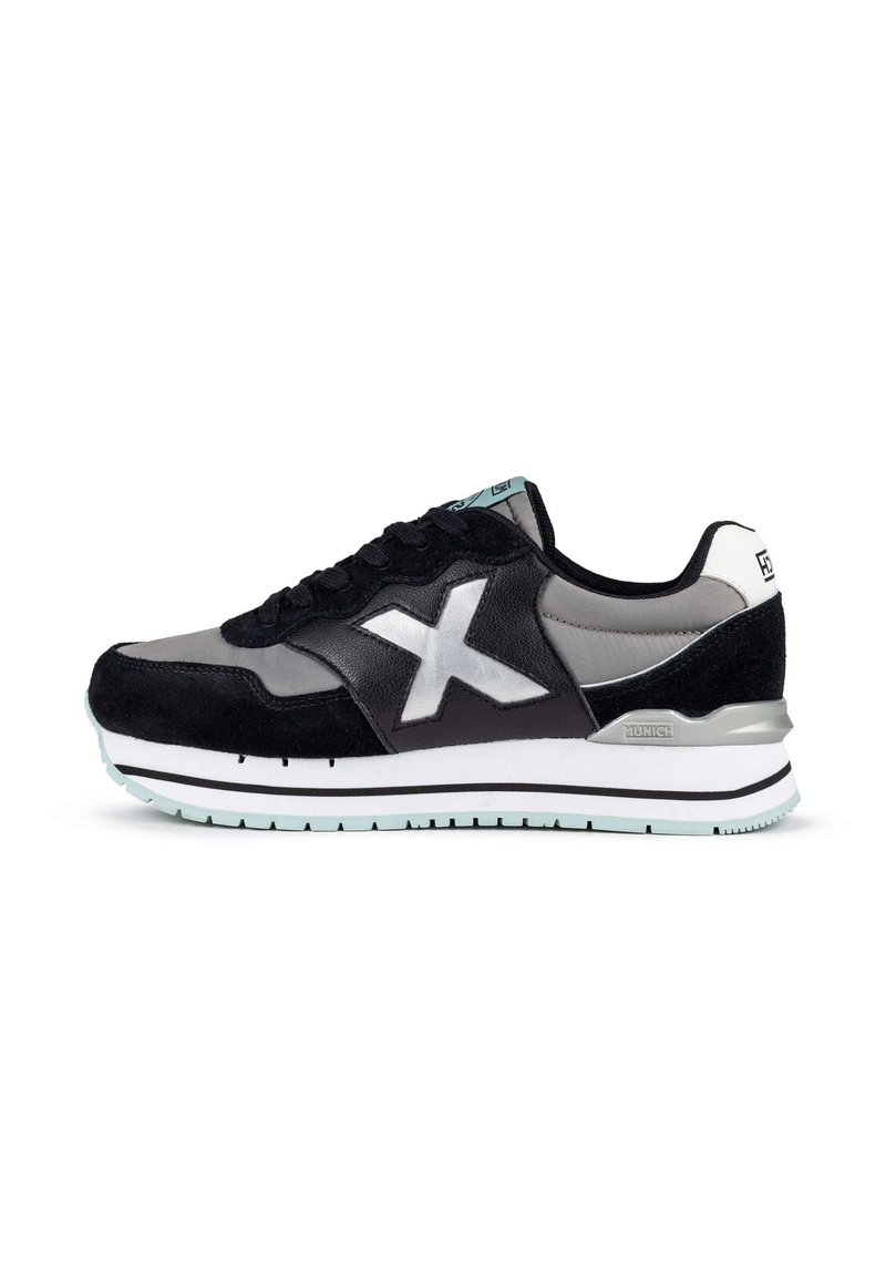 Zapatillas negras y grises que presentan materiales de ante y cuero, con una parte superior texturizada, una media suela blanca y acentos metálicos en plata.