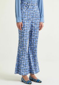 Pantaloni svasati con motivo geometrico in tonalità di blu e bianco. Tessuto liscio con vita e pieghe.