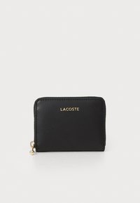 Cartera de cuero negro con cierre de cremallera y logo dorado "LACOSTE" en la parte frontal, textura suave con un detalle de tirador de cremallera redondeado.