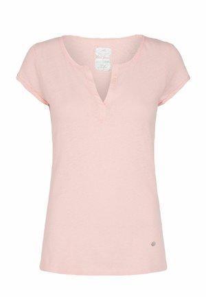 Haut pour femmes à manches courtes rose clair avec un encolure en V fendue et un petit logo rond métallique près de l'ourlet sur fond blanc.