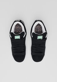 Baskets en daim noir avec des accents blancs, dotées de lacets plats, d'un col rembourré et de semelles intérieures texturées affichant un motif de logo brun.