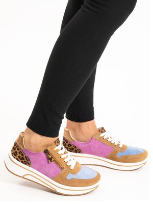 Legs in black leggings wearing colorful platform sneakers with leopard print, purple, blue, and tan panels, white laces, and side zipper.