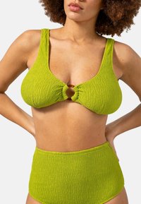 Grön texturerad bikiniöverdela med breda remmar, prydd med en rund trädetalj i mitten. Högmidjade matchande underdelar.