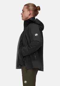 Giacca nera impermeabile con cappuccio, tasche laterali con zip e logo sulla manica sinistra. Tessuto liscio e coulisse regolabile all'orlo.