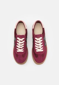 Paire de baskets en daim bordeaux avec lacets blancs, accents latéraux noirs, colliers de talon rose clair et semelles en caoutchouc gomme vues de dessus.