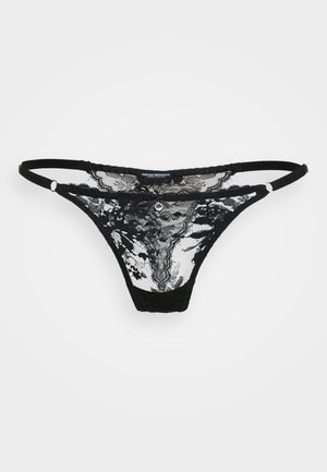 Thong in pizzo nero con motivo floreale trasparente, dotato di spalline regolabili e un accento decorativo frontale. Texture morbida.