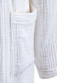 Robe en coton blanc avec un tissu texturé à rayures verticales, une poche latérale et des manches avec des poignets.
