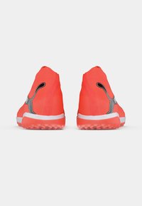 Neonorange atletiksko med tekstureret overdel, sokkelignende krave, sorte detaljer og hvid sål med teksturerede grebsmønstre.