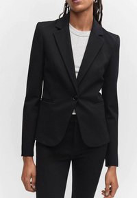 Blazer noir sur mesure avec une fermeture à un bouton, des revers crantés et deux poches devant, confectionné en tissu texturé pour une coupe structurée.