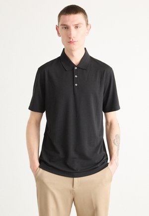 Svart polo shirt i slät tyg, med klassisk krage och treknappslå. Korta ärmar och en avslappnad passform.