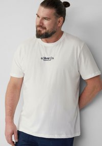 Biała bawełniana koszulka z krótkim rękawem, okrągłym dekoltem i granatowym nadrukiem z logo "s.Oliver Co. Established 1969" z przodu.