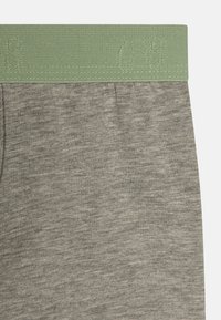 Pantalons en mélange de coton gris avec une texture douce, dotés d'une ceinture élastique vert clair avec des détails en relief.
