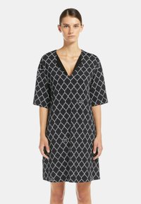 Abito nero con un motivo geometrico bianco, maniche larghe a tre quarti, scollatura a V e chiusura con bottoni, realizzato in tessuto leggero.