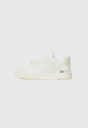White sneaker featuring a textured side panel, smooth leather upper, and a contrasting silver accent on the heel. Flat rubber sole.