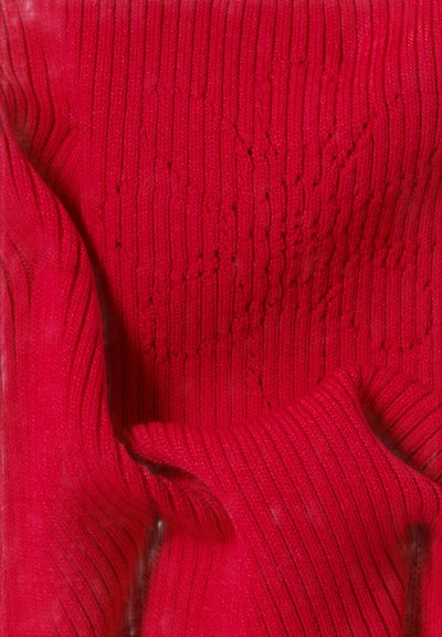 Tessuto in maglia rossa con texture a coste e motivi sottili. La superficie ha un aspetto morbido e una leggera lucentezza.