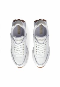 Bílé tenisky s hladkým koženým svrškem, kulatou špičkou a šesti dírkami na tkaničky. Hnědá texturovaná podrážka a zlaté akcenty na logu a detailech.