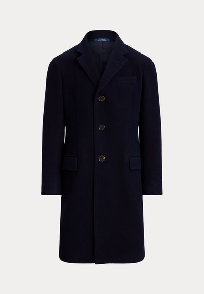 Manteau d'homme bleu marine foncé à simple boutonnage avec trois boutons, col cranté, poche poitrine et deux poches à rabat, présenté sur un fond uni.