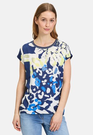 Korte mouwen, ronde hals top in blauw en wit met gele en groene abstracte bloemenpatronen; soepel stof met een lichte glans.