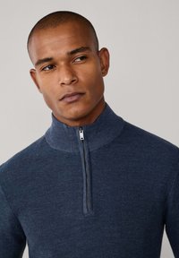 Maglione navy con zip al collo realizzato in tessuto a maglia testurizzato. Presenta un colletto alto e una zip argento, offrendo un design moderno e fitted.