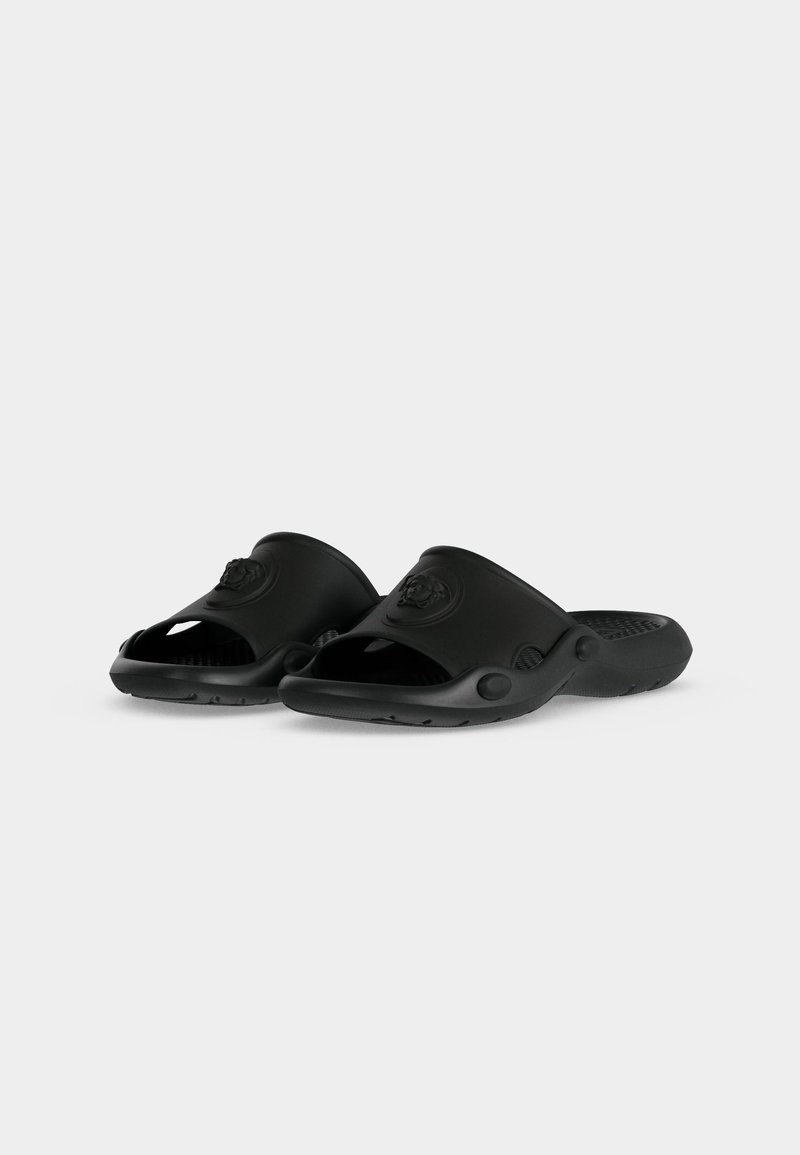 Coppia di sandali neri aperti davanti, tipo slip-on, con suole testurizzate e un piccolo emblema sulle cinghie superiori, mostrati su sfondo bianco.
