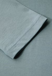 Lichtblauwe lange mouw shirt stof met een gladde textuur, met een net gestikte mouwzoom en subtiele ribbeldetails.