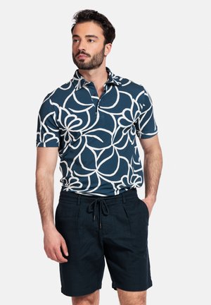 Korte mouwen polo in donkerblauw met een wit bloemenpatroon, gecombineerd met donkere shorts met een elastische tailleband en een trekkoord.