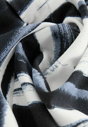 Textilná šatka s čiernobielym abstraktným vzorom s odtieňmi modrej, vyrobená z mäkkého, textúrovaného materiálu, elegantne uložená.