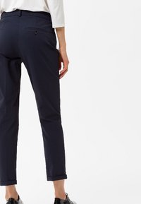 Pantalons en polyblend marine à coupe ajustée, avec ourlet roulé, poches latérales et une poche arrière avec fermeture à bouton.