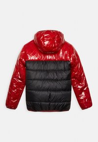 Rød og sort skinnende polstret jakke med hætte, vist fra ryggen, med horisontale sorte kviltede sektioner på den nederste halvdel.