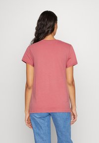 T-shirt i blød, ensfarvet mauve bomuld med korte ærmer, rund halsudskæring og lige snit, kombineret med lyseblå denimbukser.