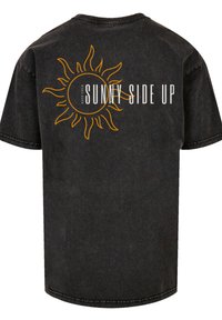 Black denim t-shirt with short sleeves, featuring an orange sun graphic and "KEEP YOUR SUNNY SIDE UP" text centered below the design.