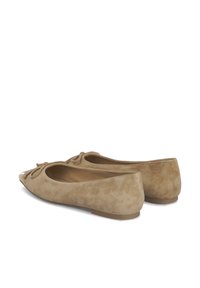 Ballerines en suède beige clair avec un bout arrondi, un nœud décoratif sur l'empeigne et une légère brillance sur le bout. Semelles plates.