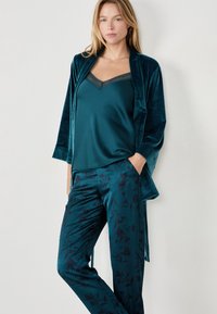 Conjunto de pijama de raso verde azulado que incluye un camisón con encaje y pantalones estampados con diseños florales. Textura suave con un corte relajado.