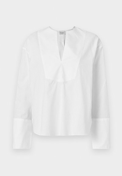 Witte blouse met lange mouwen, een gespleten halslijn en contrasterende textuurstrepen. Heeft een boxy pasvorm en brede mouwen met witte manchetten.