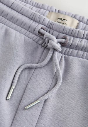 Light gray sweatpants waistband with a tied drawstring and visible "NEXT STRAIGHT FIT" label inside.