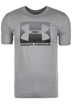 Szara koszulka Under Armour z krótkim rękawem, dużym czarnym logo i napisem "UNDER ARMOUR" na środku klatki piersiowej.